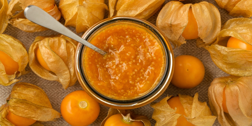 Ripe ground cherry jam in a jar surrounded by golden ground cherries from top view